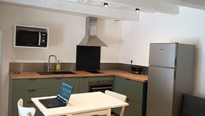 A compact kitchen with a dining area, including a table, chairs, a microwave, a stove, and a refrigerator. - Villeneuve-les-avignon, historic center (Villeneuve-lès-Avignon)