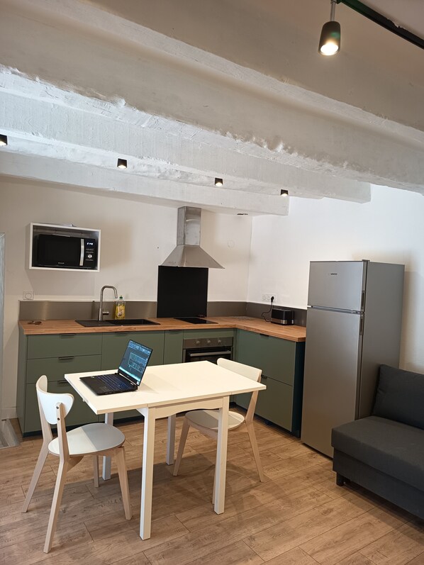 Une cuisine compacte avec un coin repas, comprenant une table, des chaises, un four à micro-ondes, une cuisinière et un réfrigérateur.