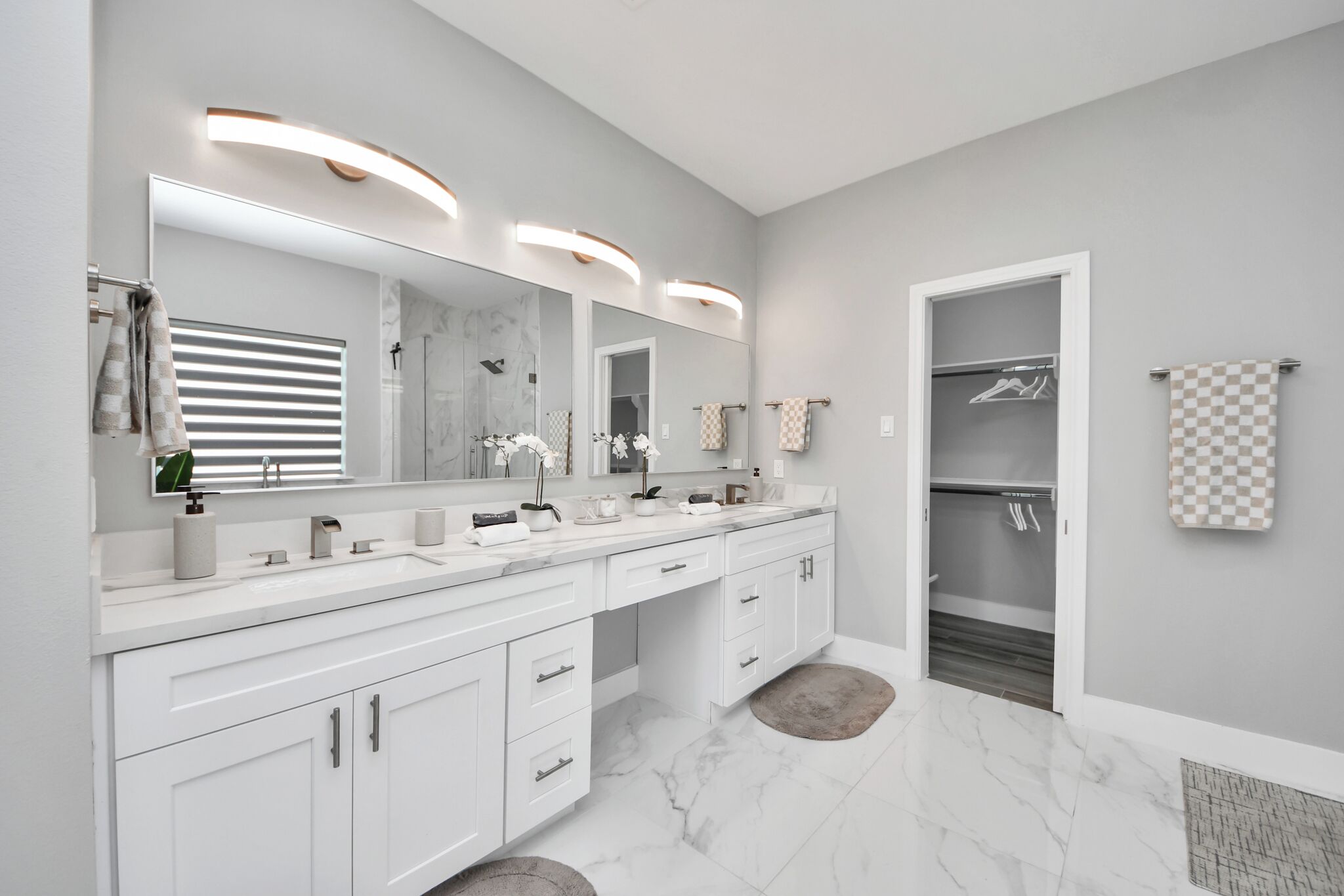Un baño moderno con un espejo grande, dos lavamanos y un vestidor.
