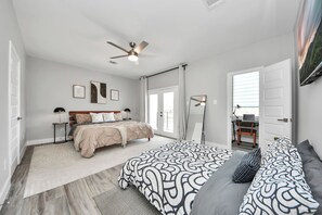 A bedroom with a bed, a desk, a ceiling fan, and a large window. - Private Pool at Pershing Pad. 3BR Sleeps 10. 10 mins from NRG . Huge backyard (Houston)