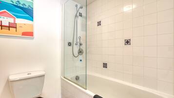 A bathroom with a glass-enclosed shower, white tiled walls, a toilet, and a towel rack.