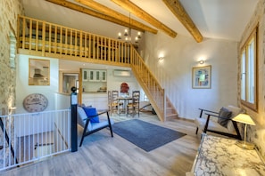 Un vaste espace de vie comprenant un escalier, des poutres apparentes, une table à manger et un canapé.