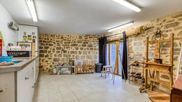 Una stanza con pareti in pietra, un cavalletto di legno, un lavandino e una finestra con vista.