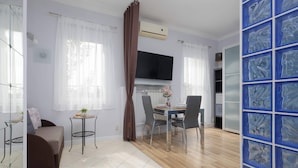 Een moderne woonkamer met een bank, een eettafel met stoelen, een televisie en een blauwe decoratieve wand.
