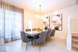 Un coin repas avec une table en verre, des chaises grises et un lustre.