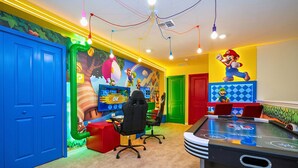 A room with a gaming console, a pool table, and colorful murals. - Upstay Family Fun 5BR Retreat w Pool & Games Room (Clermont)