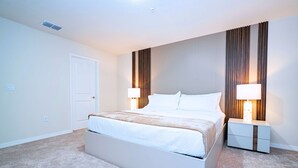A bedroom with a bed, nightstands, and a door. - Upstay Family Fun 5BR Retreat w Pool & Games Room (Clermont)