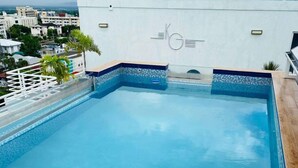 A rooftop pool with clear blue water, surrounded by a white wall with a logo. - 1 Bedroom Mountain Retreat New Kingston (Kingston)