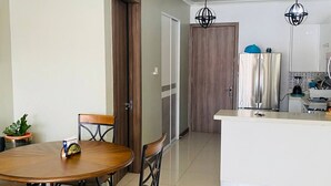 A modern kitchen with a central island, a dining area with a round table and chairs, and a door leading to another room. - 1 Bedroom Mountain Retreat New Kingston (Kingston)