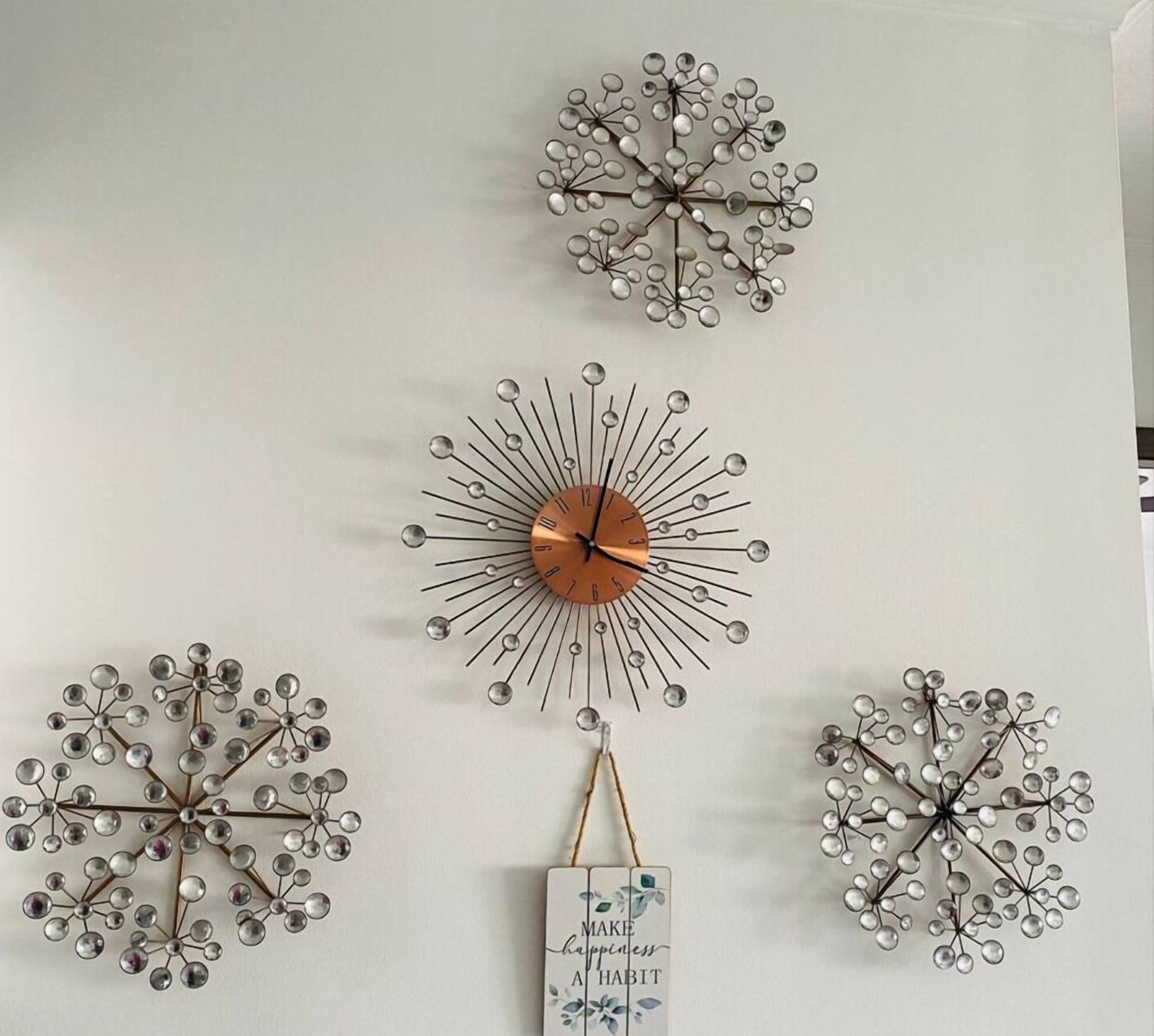 A wall with four decorative metal wall clocks of different designs.
