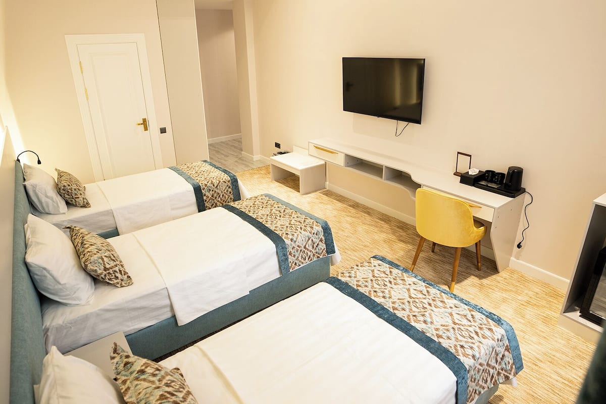Deluxe Triple Room, Garden View | In-room safe, desk, laptop workspace, blackout drapes