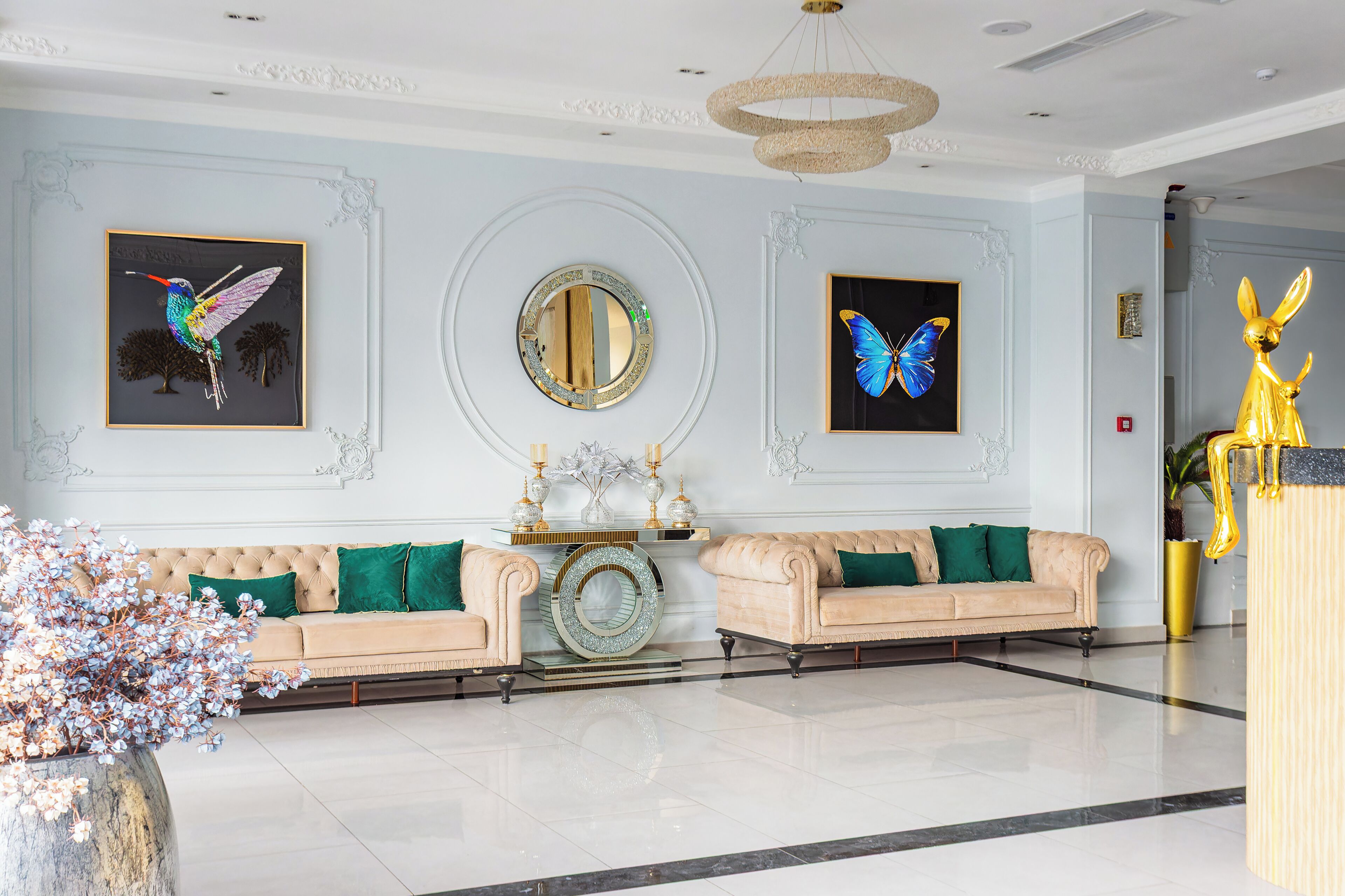 A lobby with two sofas, a large mirror, and butterfly wall art.