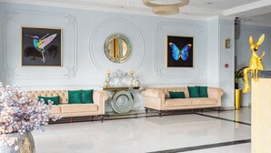 A lobby with two sofas, a large mirror, and butterfly wall art.