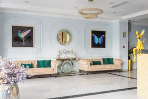 A lobby with two sofas, a large mirror, and butterfly wall art.