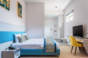 Una camera d'albergo moderna con un letto, comodino, scrivania e sedia.
