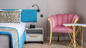 A hotel room with a bed, a bedside table with a telephone, a chair, and a small round table.