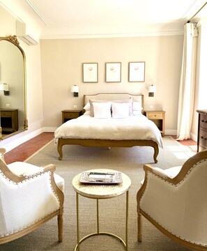 A spacious bedroom with a large bed, two bedside tables, a round coffee table, and a large mirror. - Château Saint Perret (Avignon)