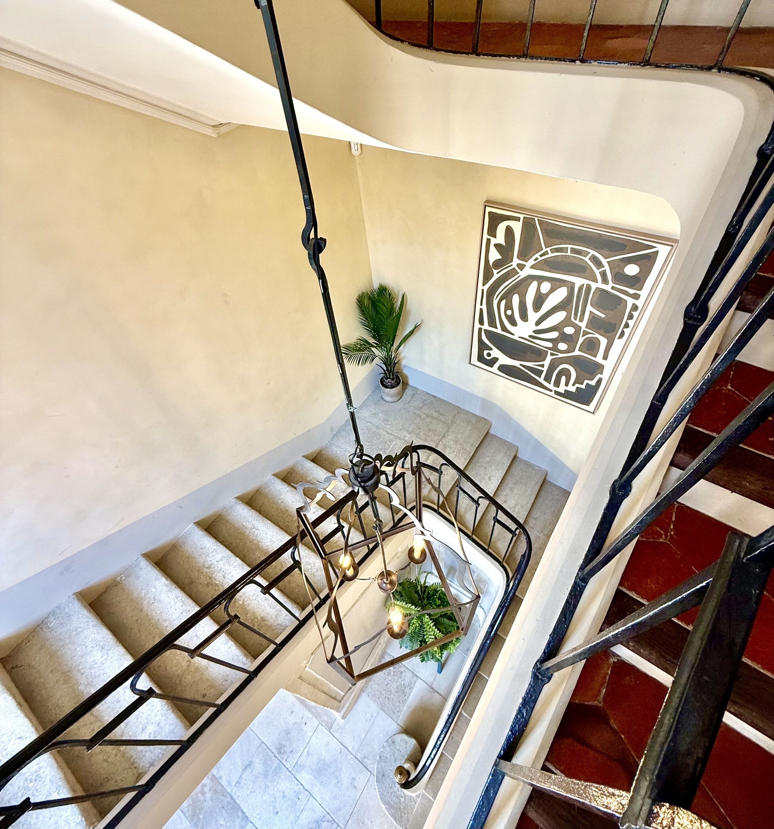 A staircase with a metal railing, a potted plant, and a wall-mounted artwork.