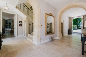 A spacious interior with a grand staircase, a large ornate mirror, and a view of the outdoors. - Château Saint Perret (Avignon)
