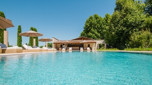 A swimming pool with lounge chairs and umbrellas, surrounded by greenery. - Château Saint Perret (Avignon)