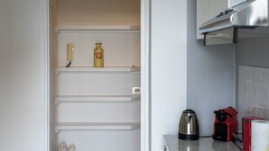 A kitchen with a white refrigerator, a kettle, a red coffee maker, and a trash bin. - Complete vacation apartment between lake and mountains (Caslino D'erba)