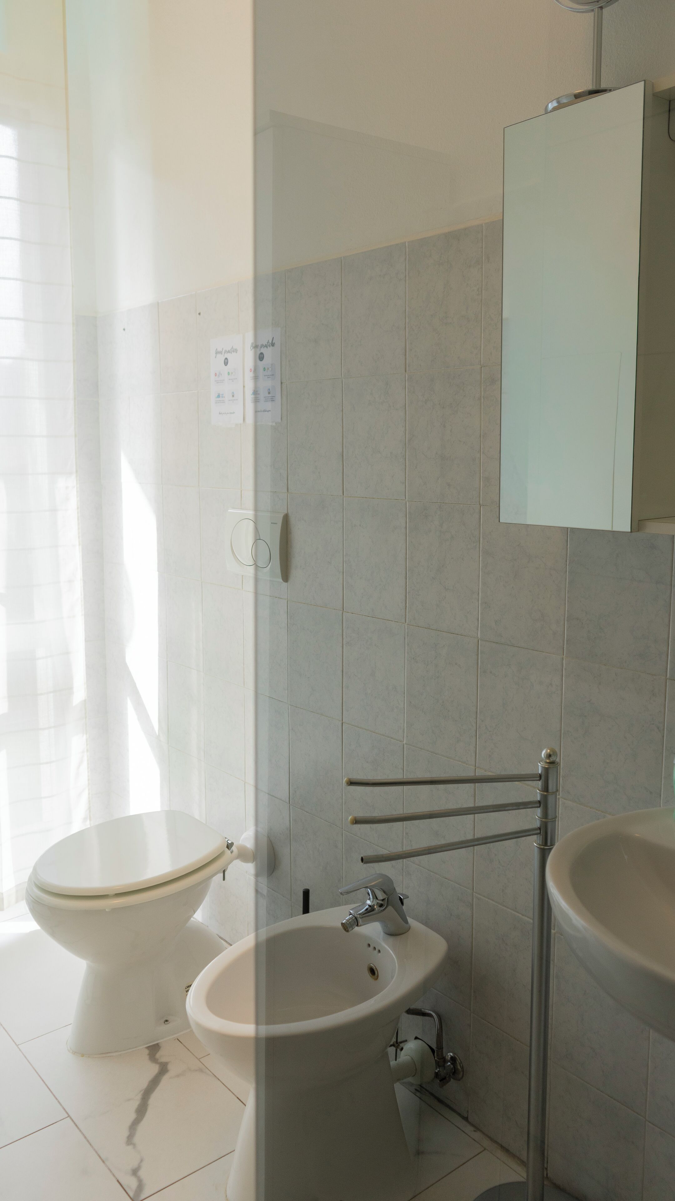 Een witte badkamer met toilet, bidet en wastafel.