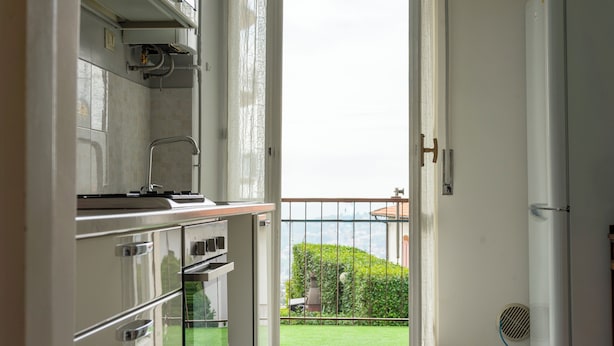 A kitchen with a view of a balcony and a cityscape. - Complete vacation apartment between lake and mountains (Caslino D'erba)