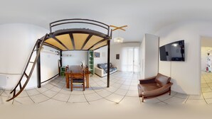 A spacious living area with a dining table, a sofa, and a TV mounted on the wall. - Complete vacation apartment between lake and mountains (Caslino D'erba)