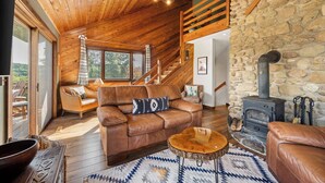 Una sala de estar acogedora con un sofá de cuero marrón, una mesa de centro de madera y una chimenea de piedra.
