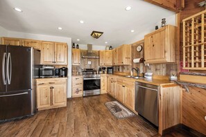 Une cuisine moderne avec des meubles en bois, des appareils électroménagers en acier inoxydable et un plancher en bois.