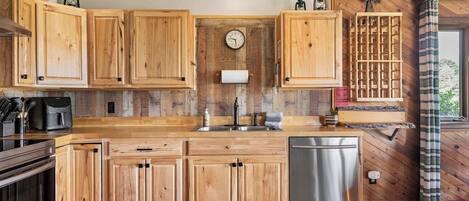 Una cocina con armarios de madera, lavavajillas de acero inoxidable y encimera de madera.