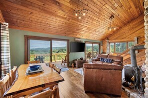 L’intérieur d’un chalet en bois comprend une table à manger, un canapé en cuir et une cheminée.
