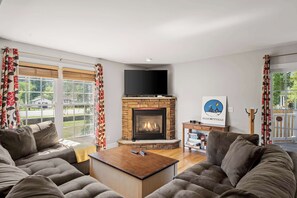 A living room with a fireplace, sofa, coffee table, and a flat-screen TV.