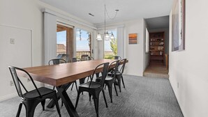 A dining area with a wooden table and black chairs, a carpeted floor, and a view through the open door. - Cozy Condo - Desert Mesa View! (St. George)