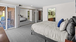 A bedroom with a bed, a desk, and a sliding glass door leading to an outdoor area. - Cozy Condo - Desert Mesa View! (St. George)