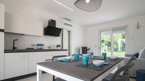 A modern kitchen with white cabinets, a black range hood, and a dining area with a table set for four. - Armonia Suites - Acqua- new apartment with garden and pool in Verona (Verona)
