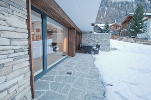 A stone exterior with a glass door, wooden accents, and a stone pathway leading to a building.