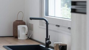 A modern kitchen with a black sink, a kettle, and two mugs on the counter. - Armonia Suites -Earth and Water new apartments with garden and pool in Verona (Verona)