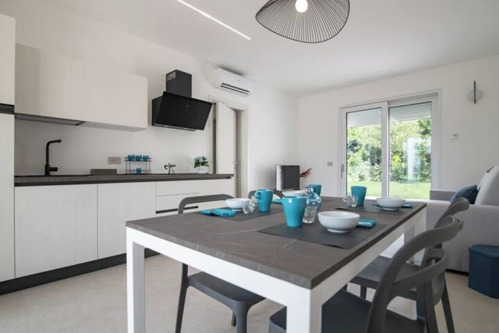 A modern kitchen with white cabinets, a black range hood, and a dining area with a table set for four.