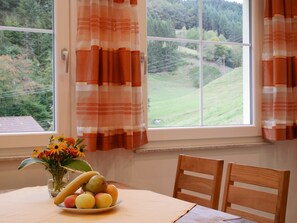 A dining table with chairs, a fruit bowl, and a vase with flowers. - Apartment 'Eulennest' with Shared Pool, Private Terrace and Wi-Fi (Wolfach)