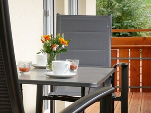 A table with a vase of flowers, two candles, and a white cup on a balcony. - Apartment 'Eulennest' with Shared Pool, Private Terrace and Wi-Fi (Wolfach)