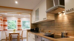 Eine moderne Küche mit Holzausstattung, einem Backofen und einem Fenster mit Vorhängen.