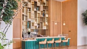 A modern bar area with a wooden wall and a teal bar counter.
