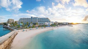 Ein Hotel direkt am Strand mit Poolbereich, Palmen und Blick auf den Ozean.