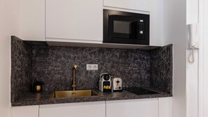 A compact kitchen with a dark marble countertop, a built-in microwave, and a sink with a gold faucet. - Charming Flat - 2bd/6p - Passy / Eiffel Tower (Paris)