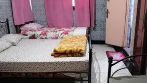 Ein Einzelbett mit einem gemusterten Bettbezug, einer gelben Decke und rosa Vorhängen.