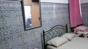 Ein Schlafzimmer mit einem Bett, einem Spiegel und Wandverkleidung mit Muster.