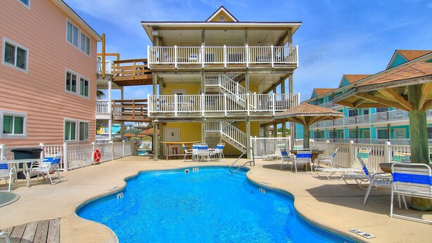 A multi-story hotel with a pool area, including lounge chairs and a lifeguard stand. - Beachgate Condo Suites And Hotel 211+212+213 3 Bedroom Condo (Port Aransas)