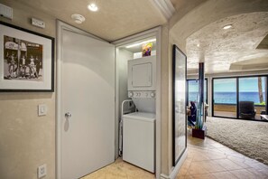 A compact laundry room with a washing machine, a dryer, and a small shelf with detergent. - Makena Surf, #b-208 2 Bedroom Condo (Kihei)