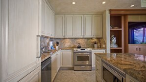 A kitchen with white cabinetry, a built-in oven, and a granite countertop. - Makena Surf, #b-208 2 Bedroom Condo (Kihei)